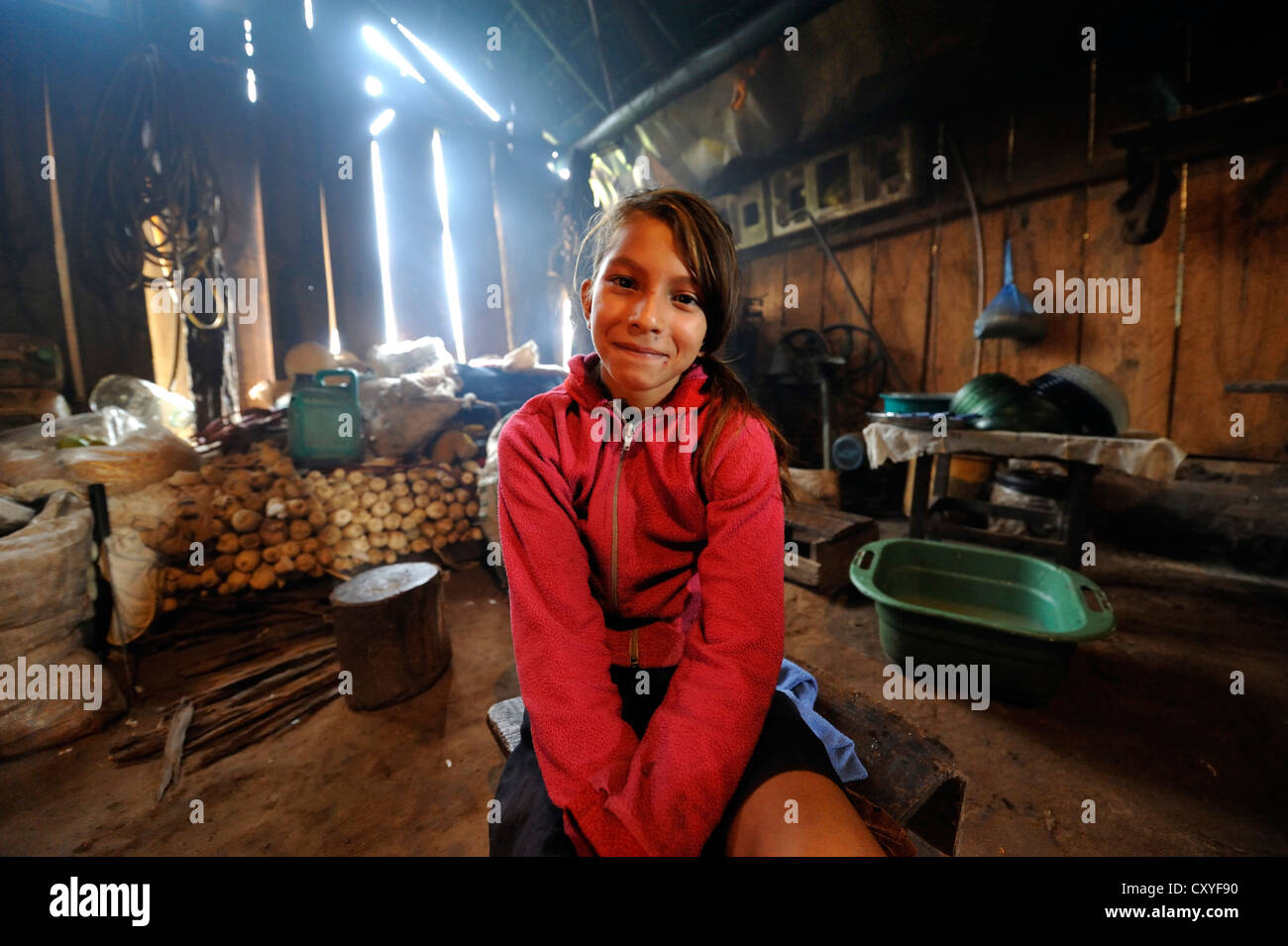 Girl sitting in a simple kitchen of a farmhouse, Comunidad Martillo, Caaguazu, Paraguay, South America Stock Photo