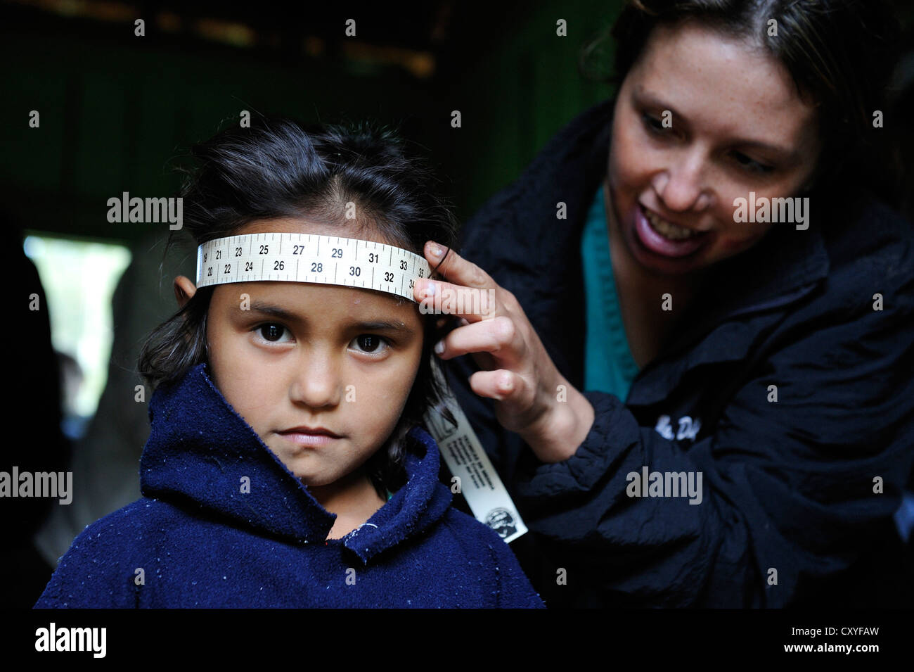 Worker of an aid organisation measuring the circumference of a girl's head, to track her physical development, the aid Stock Photo