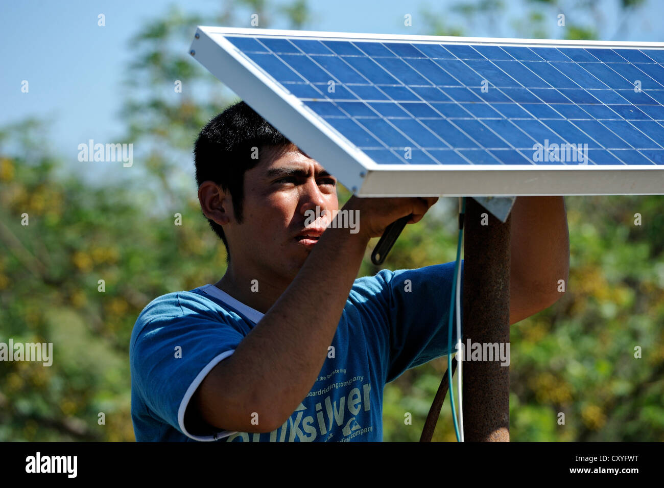 Young man mountain solar cells on the roof of a simple hut of a smallholder's farm, Gran Chaco, Santiago del Estero Province Stock Photo
