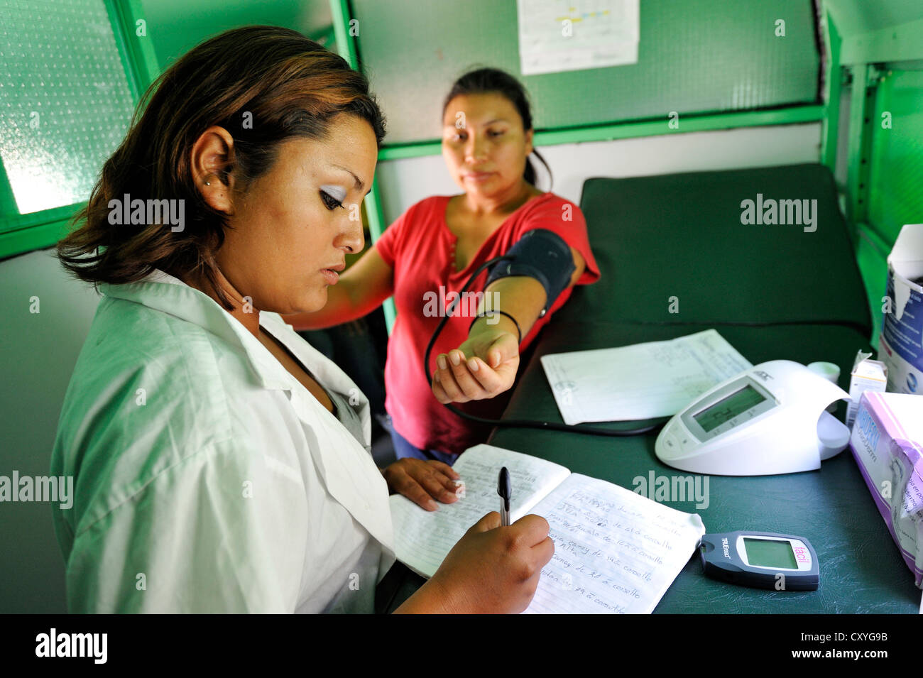 Nurse checking the blood pressure of a young woman, Guatemala, Central America Stock Photo