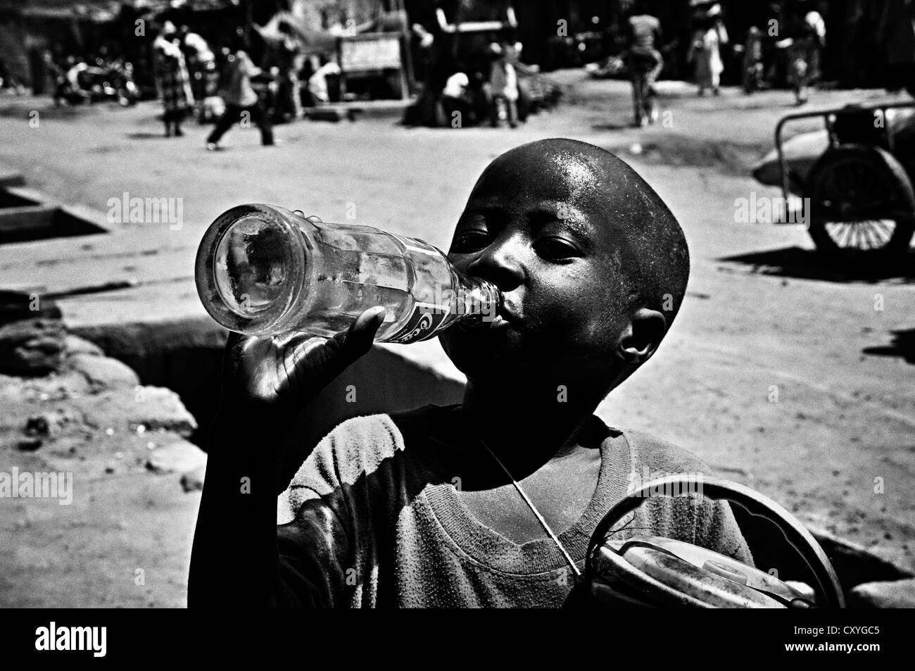 Street children drinking Coca-Cola, Djenne, Mali Stock Photo