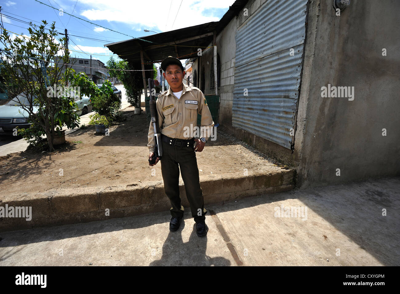 Young man holding a large gun, security guard of a trucking company, Lomas de Santa Faz slum, Guatemala City, Guatemala Stock Photo