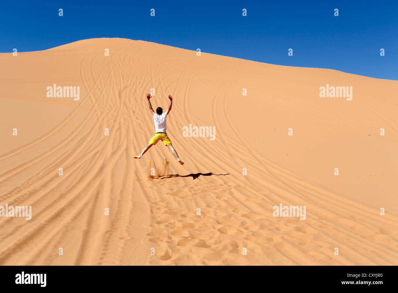 Man jumping in the sand of a dune in Coral Pink Sand Dunes State Park