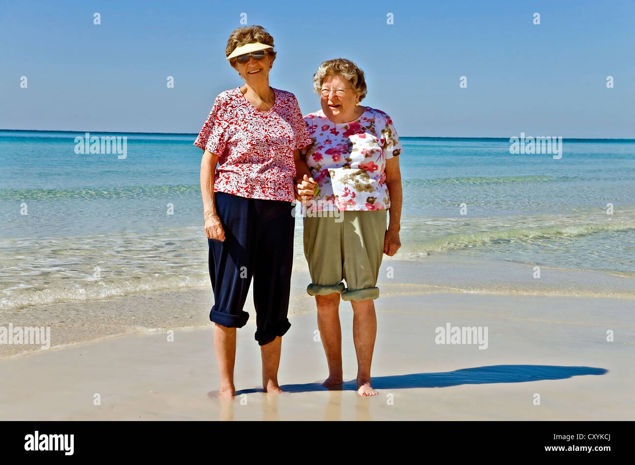 Two elderly women standing together barefoot on a beach Stock Photo Alamy