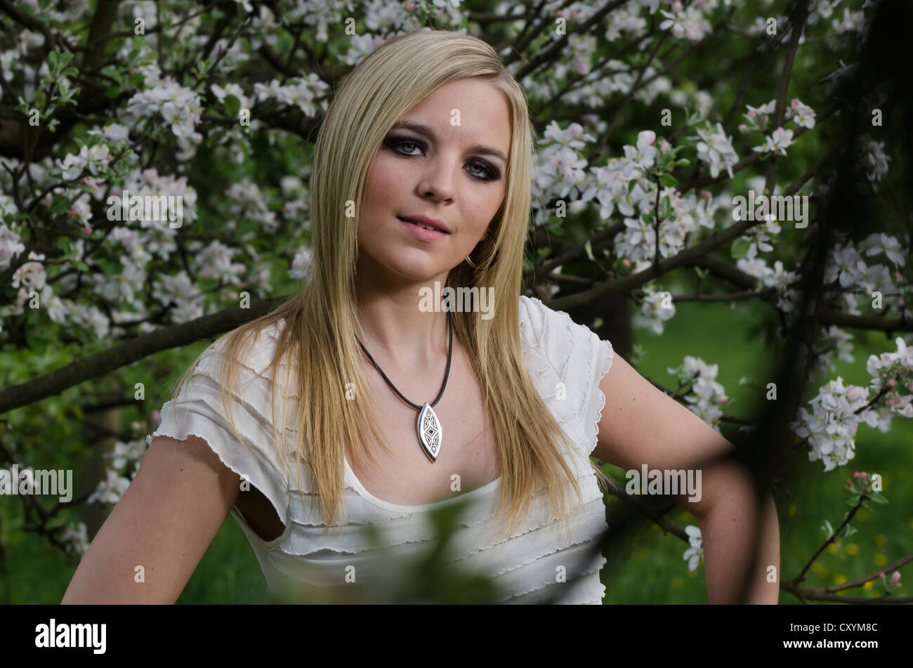 Young woman, 23 years, in front of a flowering tree Stock Photo