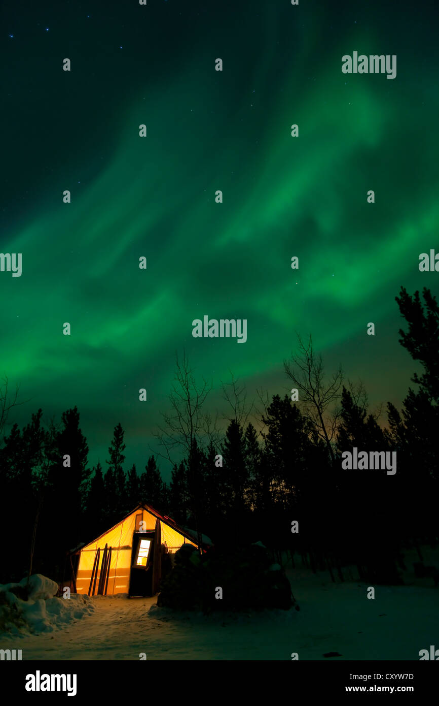 Illuminated, lit wall tent, cabin with swirling northern polar lights