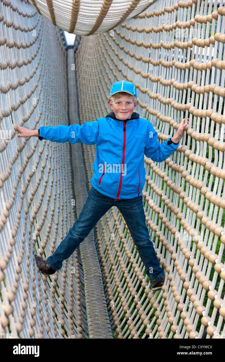 Boy, 8, standing in a tunnel made from ropes Stock Photo