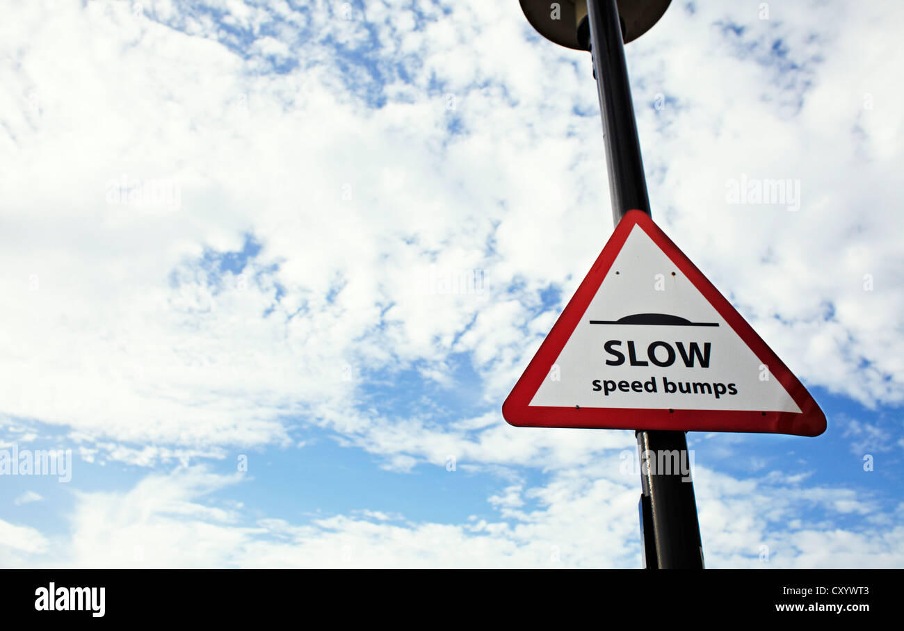 Slow speed bumps sign against sky Stock Photo