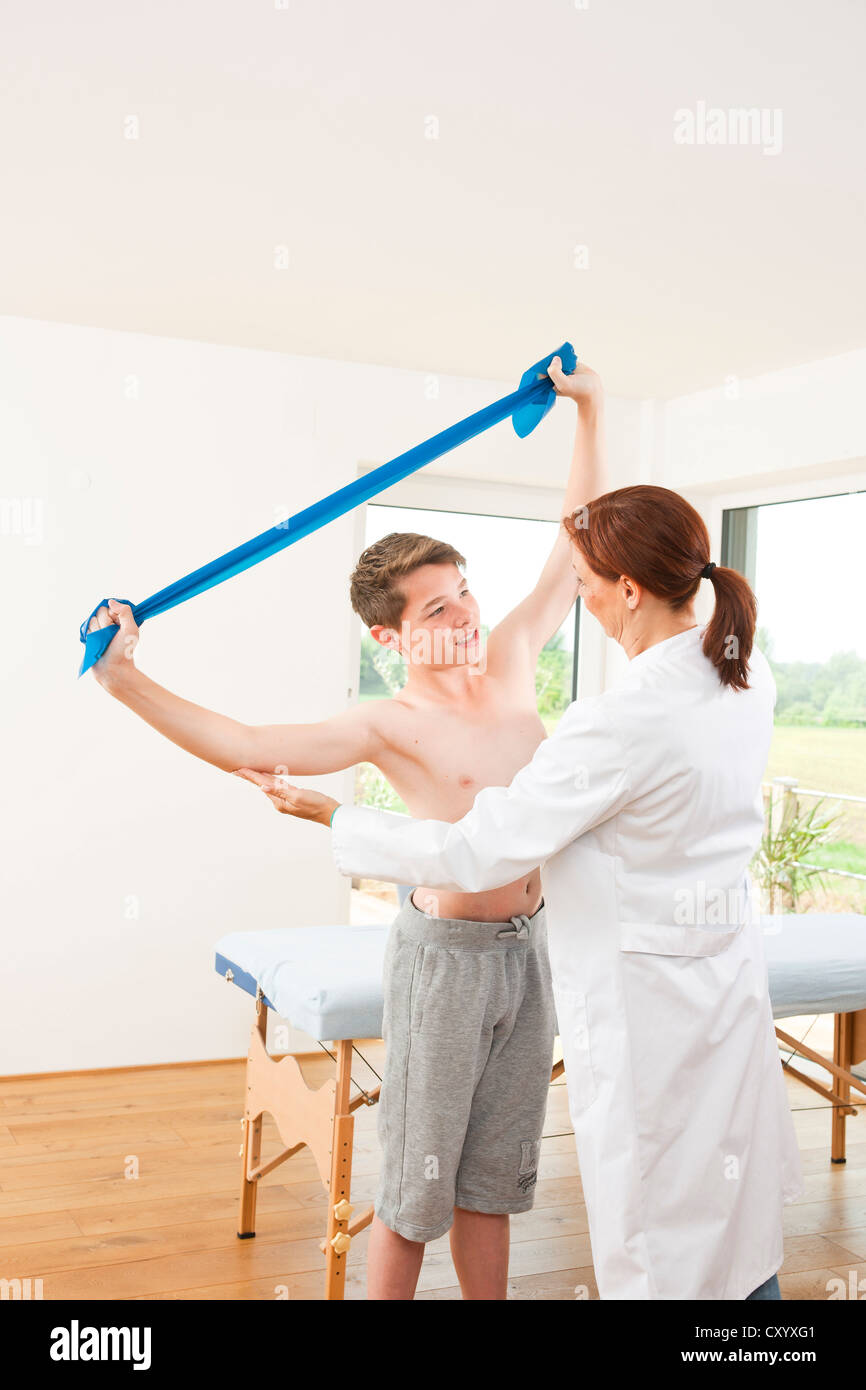 Physiotherapist working with a teenage boy with a Theraband Stock Photo