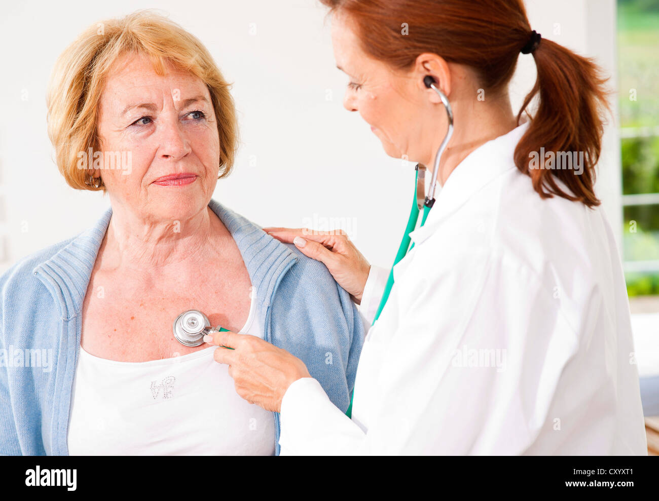 Patient being monitored by her family doctor with a stethoscope Stock