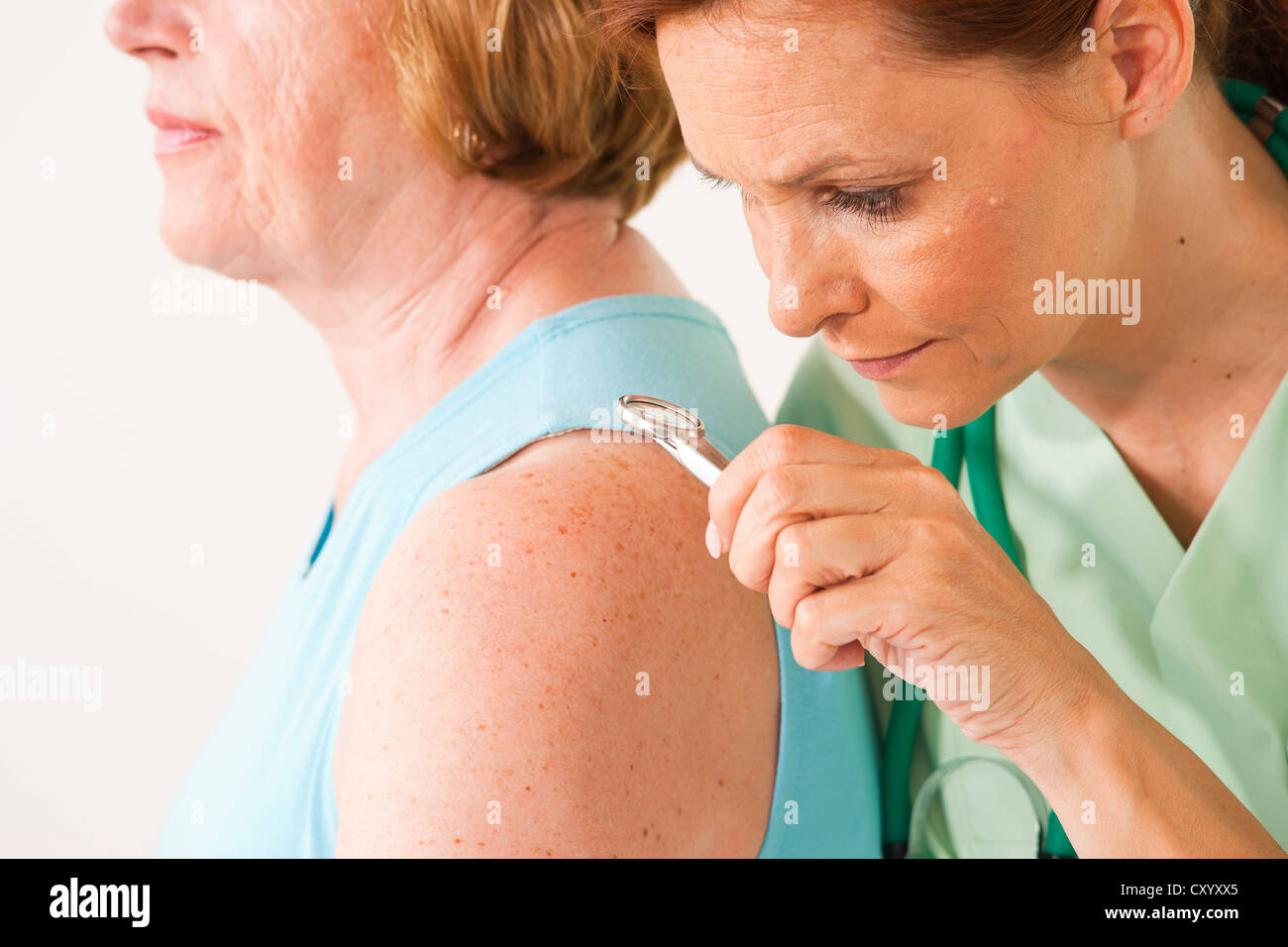 Dermatologist examining a patient with a magnifying glass Stock Photo