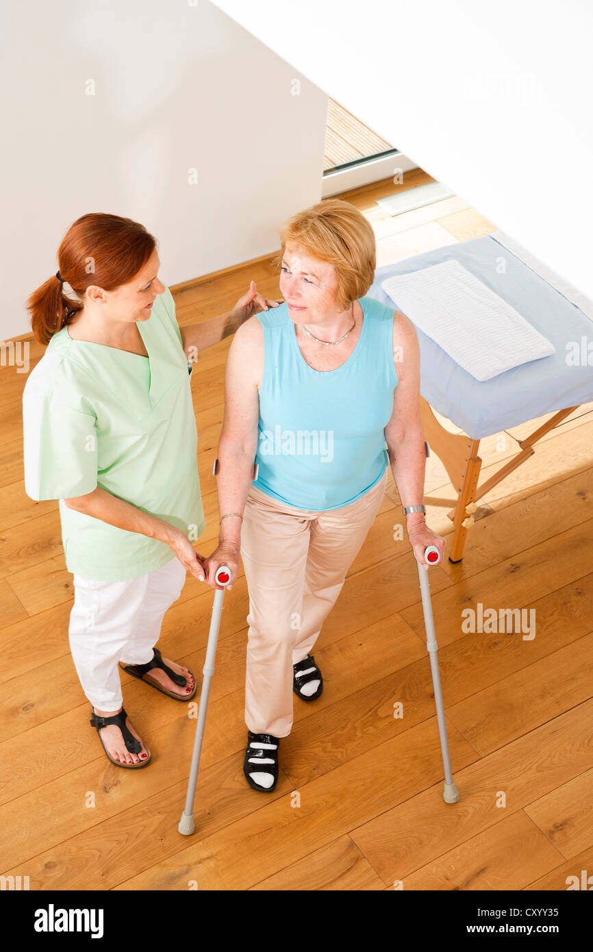 Patient on crutches being supported by her physiotherapist Stock Photo
