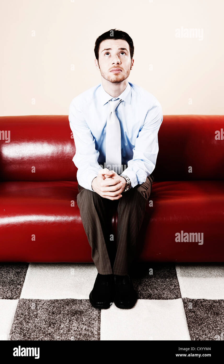 Young man sitting pensively on a sofa and waiting Stock Photo