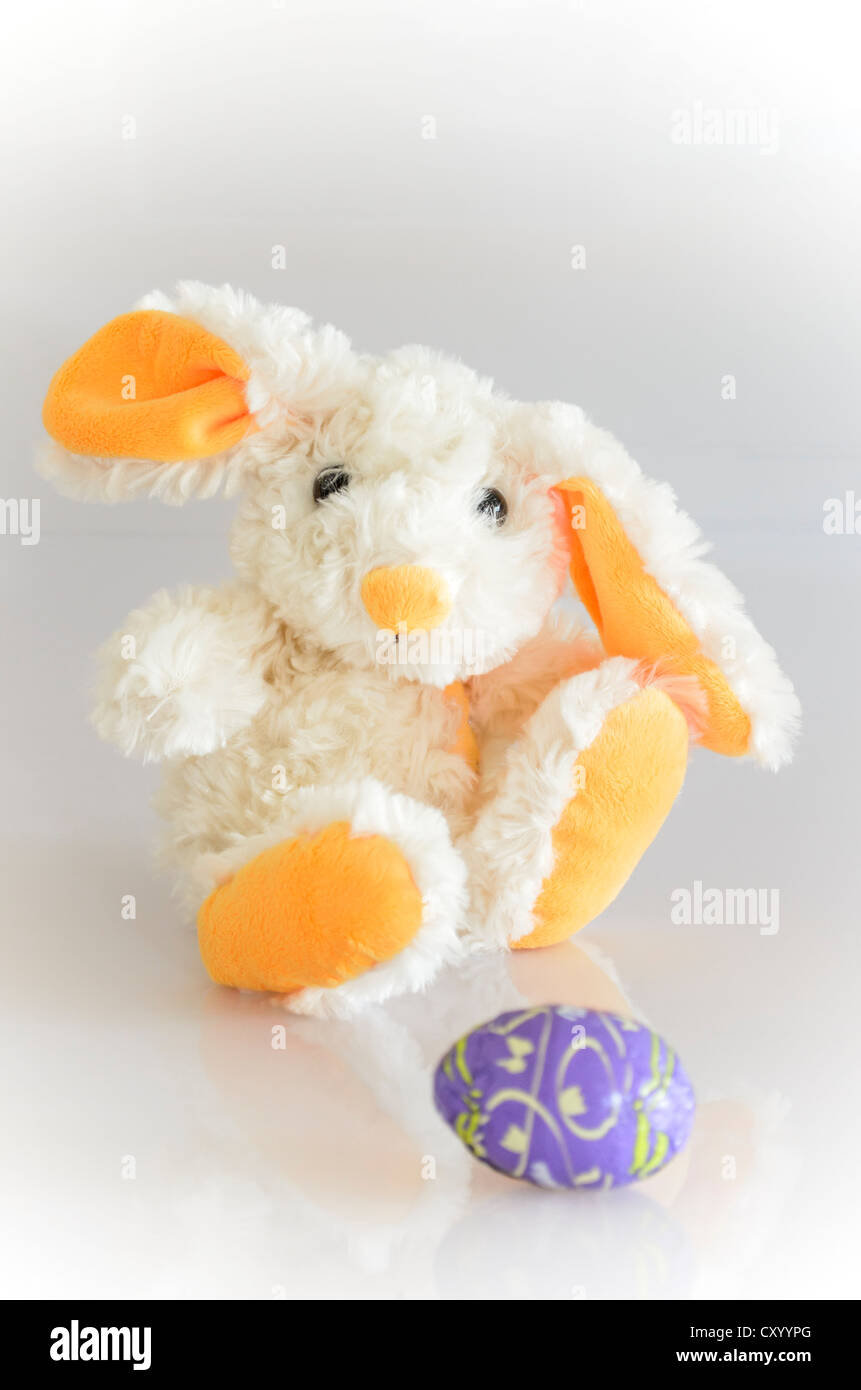 Cuddly toy, bunny, with a purple chocolate egg Stock Photo