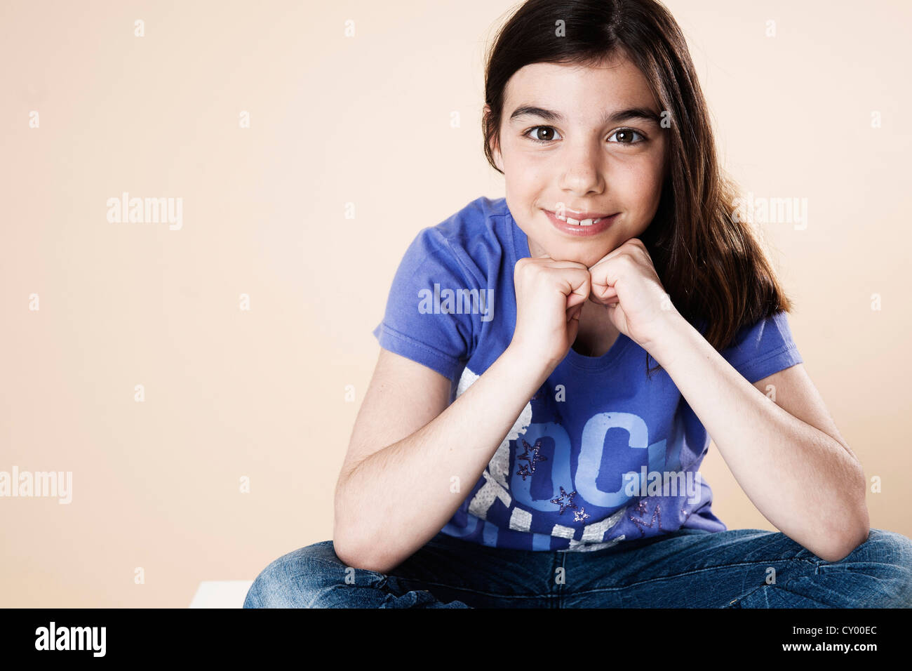 Smiling girl resting her chin on her hands Stock Photo - Alamy
