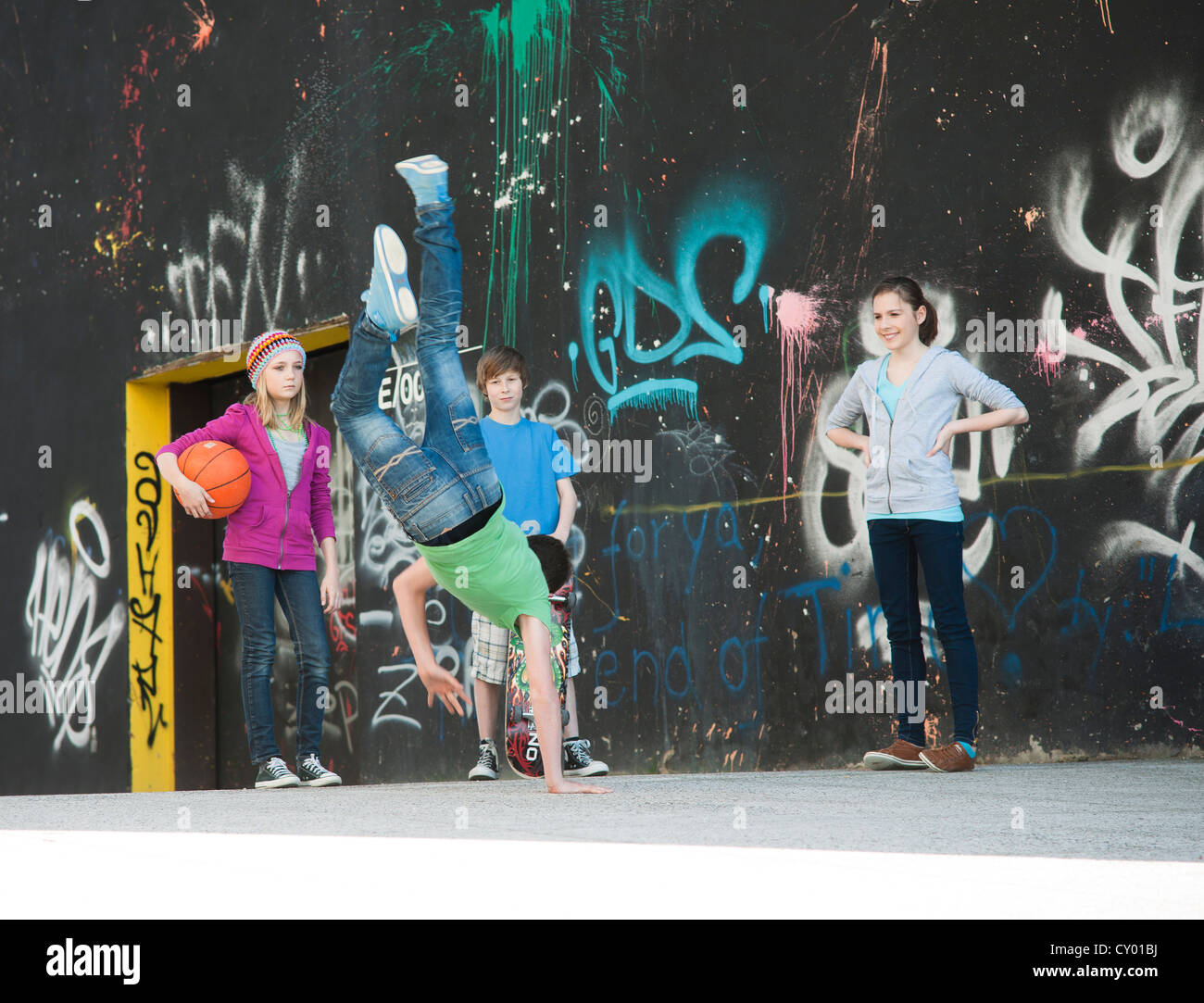 Teenagers standing in front of a wall with graffiti Stock Photo
