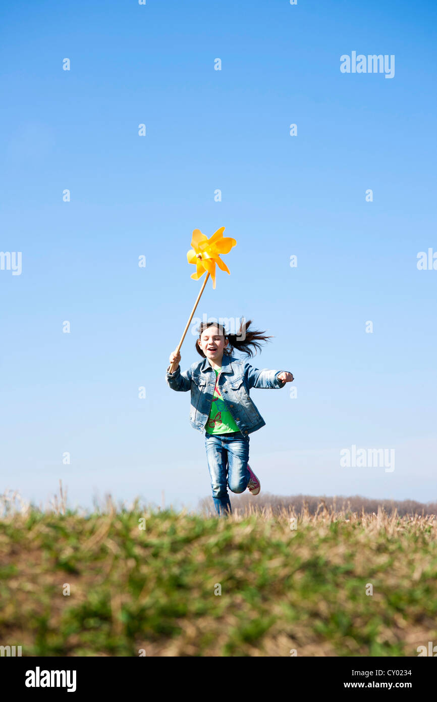 Girl running happily while holding up a pinwheel in a field Stock Photo ...