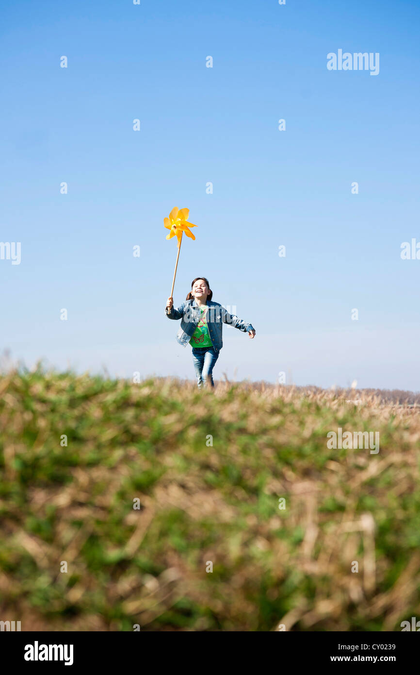 Girl running happily while holding up a pinwheel in a field Stock Photo ...