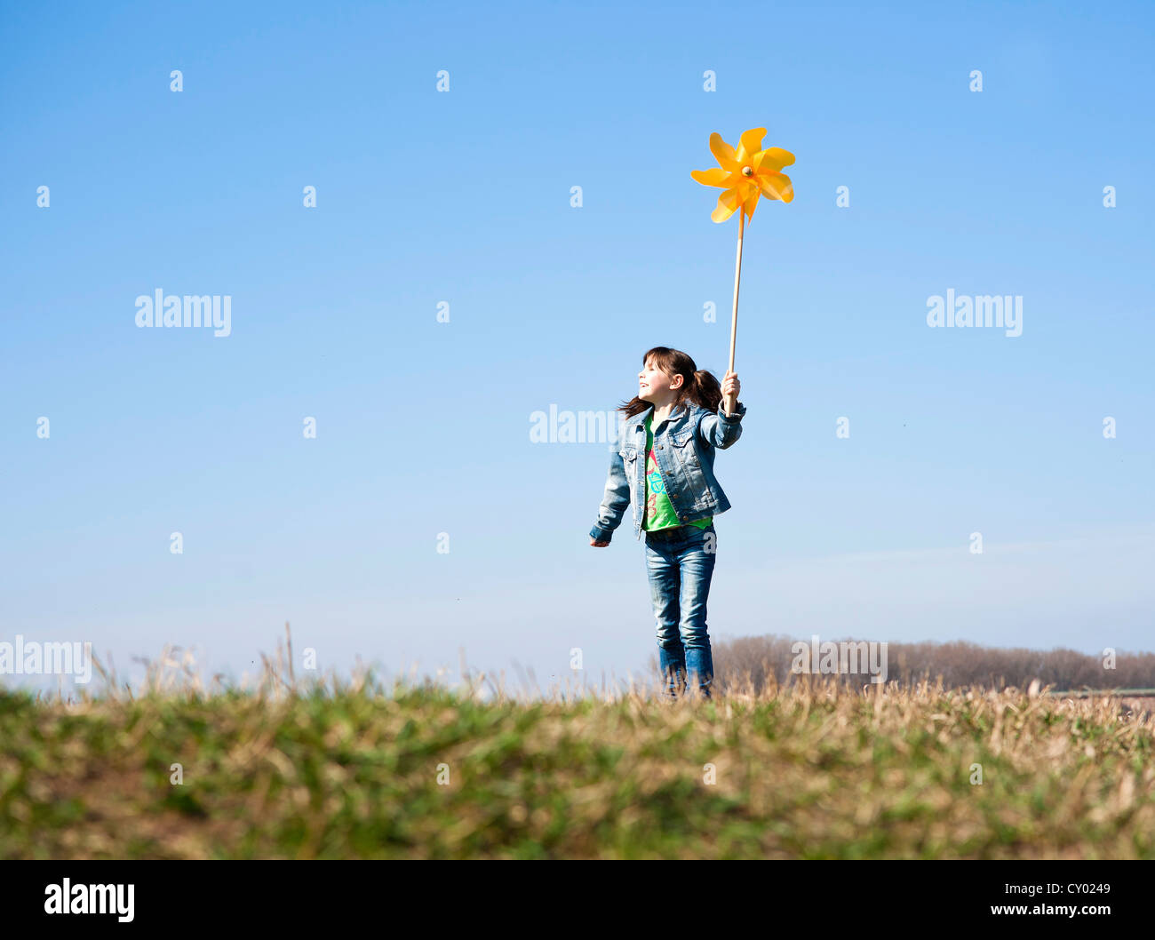 Girl holding up a pinwheel in a field Stock Photo - Alamy
