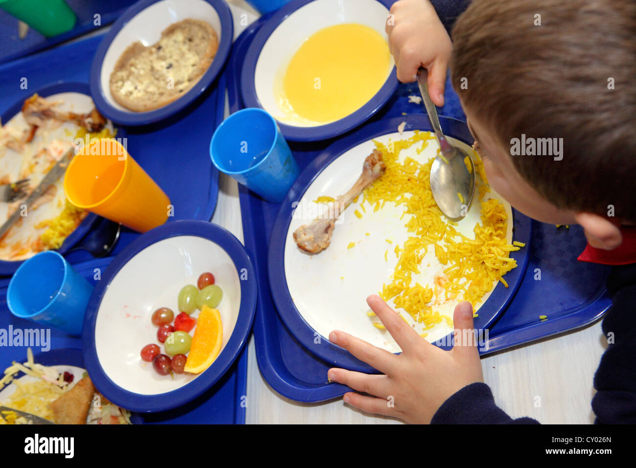 Boy (cannot be recognized) eating healthy school lunch of rice and chicken, London Primary School. Free school meals Stock Photo