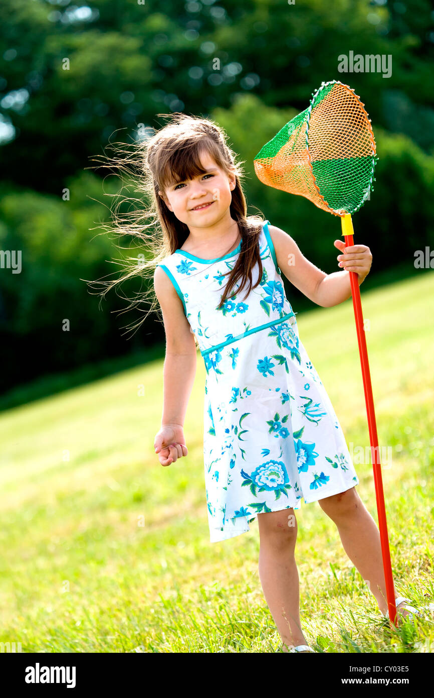 Girl playing with butterfly net in the garden Stock Photo