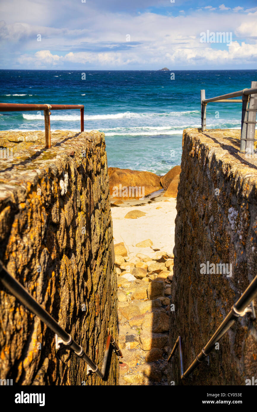 Harbour walls and steps down to beach and rugged coast coastline at ...