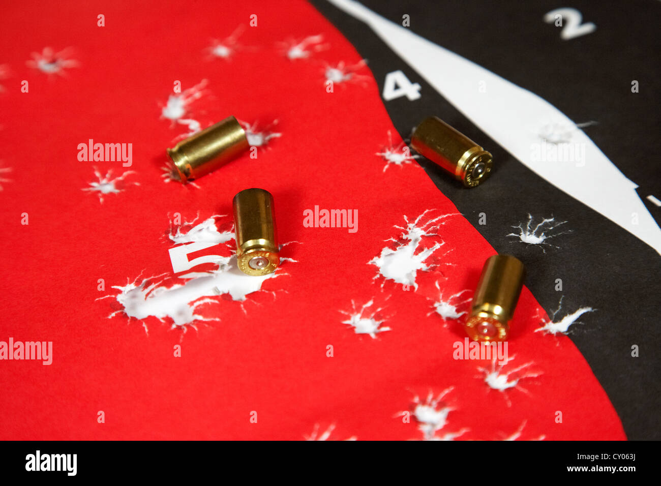 human shaped target ridden with bullet holes and 9mm empty shell casings Stock Photo