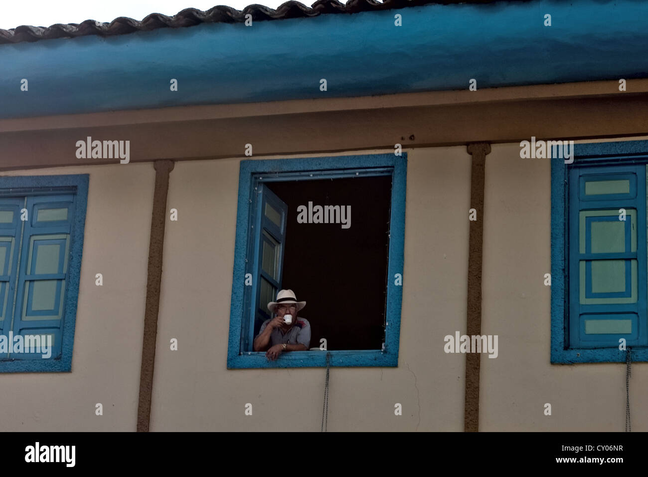Man drinking coffee, Colourful building, Solento, Colombia Stock Photo