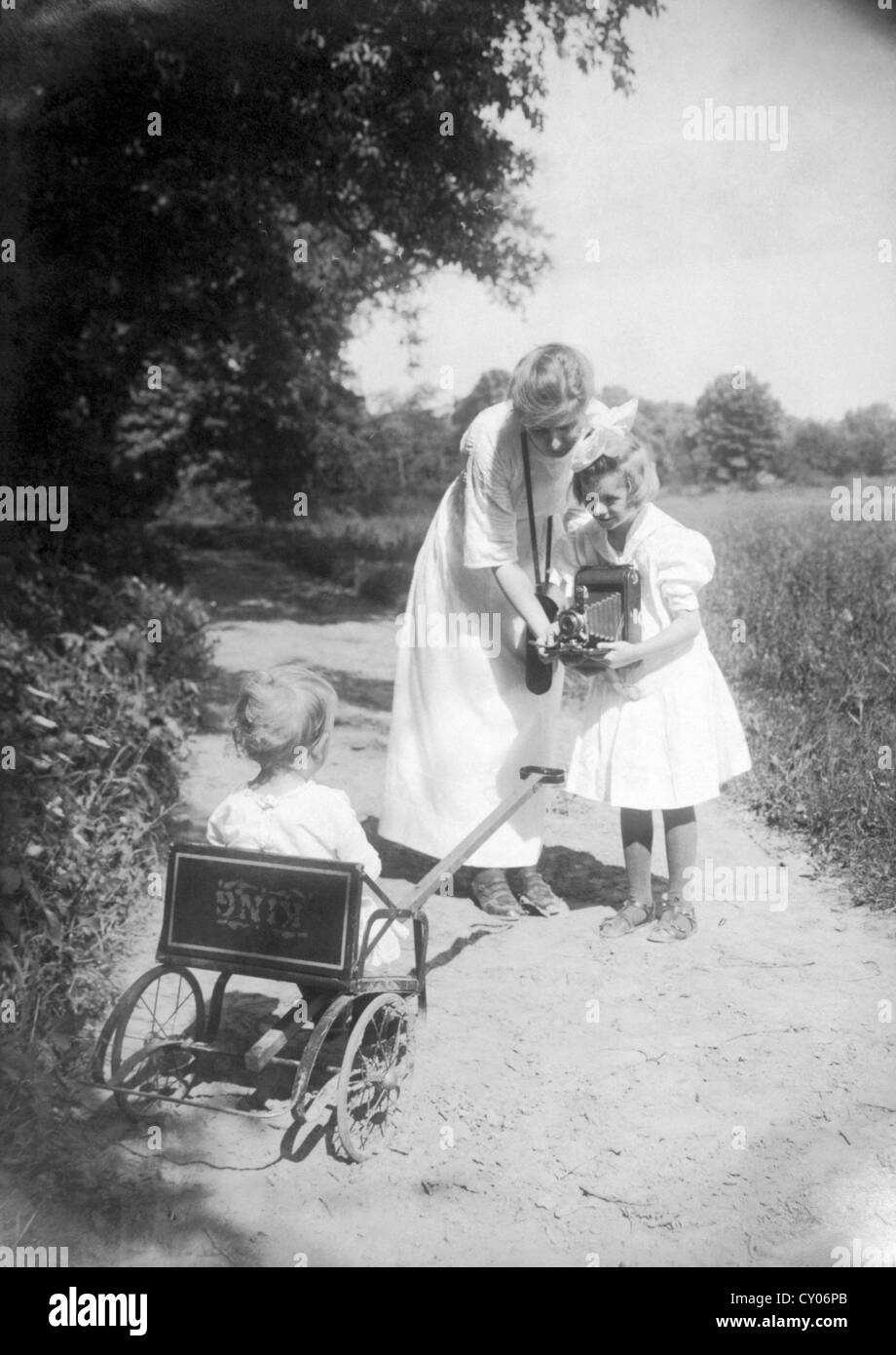 Mother Helping Daughter Take Photo of Baby with Kodak Folding Camera, Circa 1911 Stock Photo