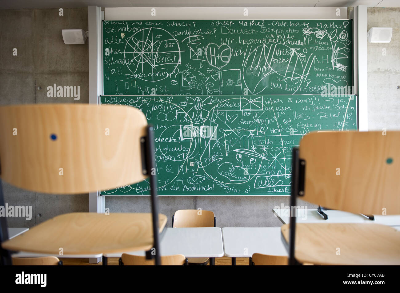Classroom of a grammar school with chairs and a blackboard covered with writing Stock Photo