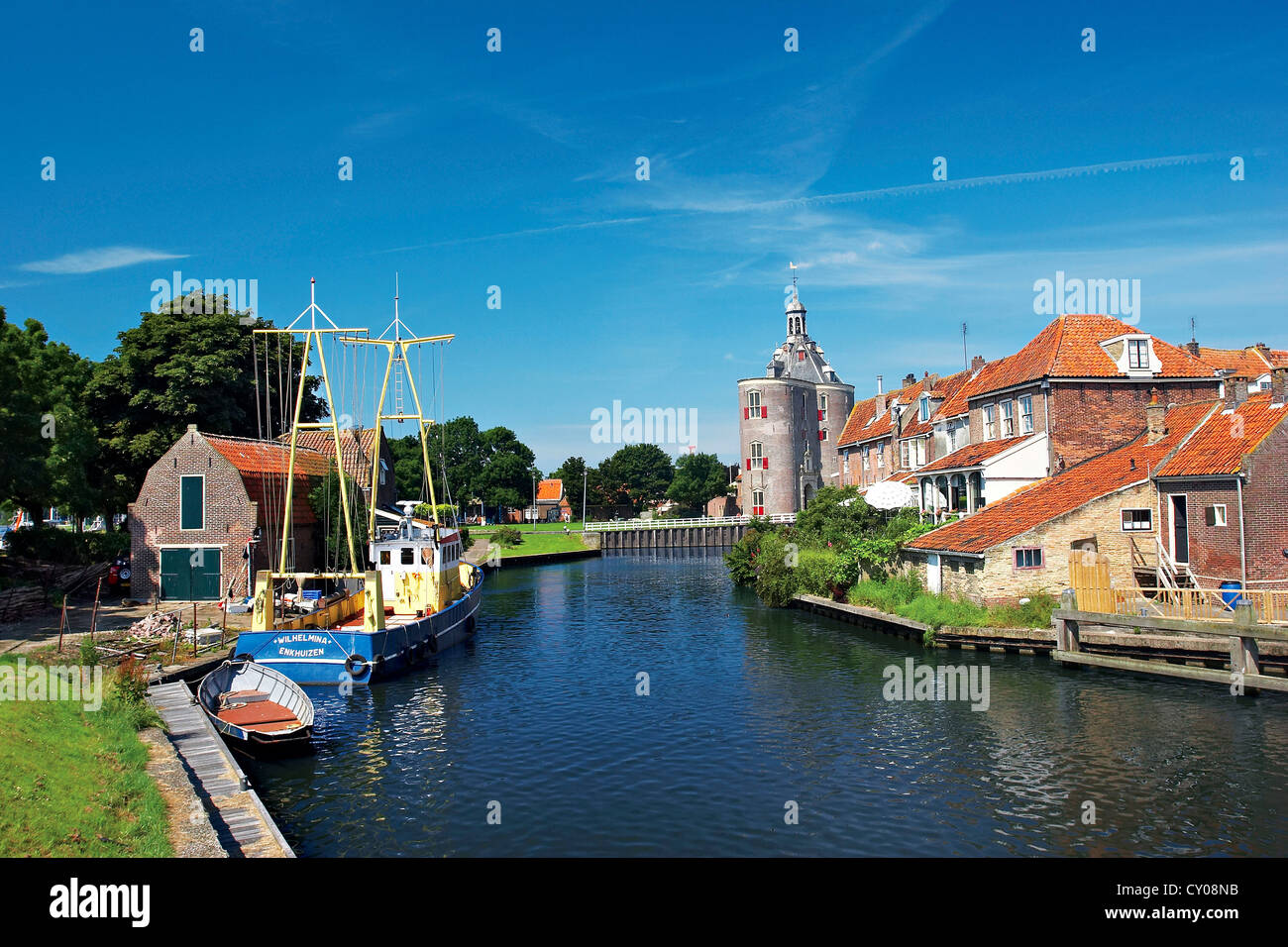 Netherlands, Enkhuizen, Classic Dutch vessels in the canal, Drommedaris Tower in the background. Stock Photo