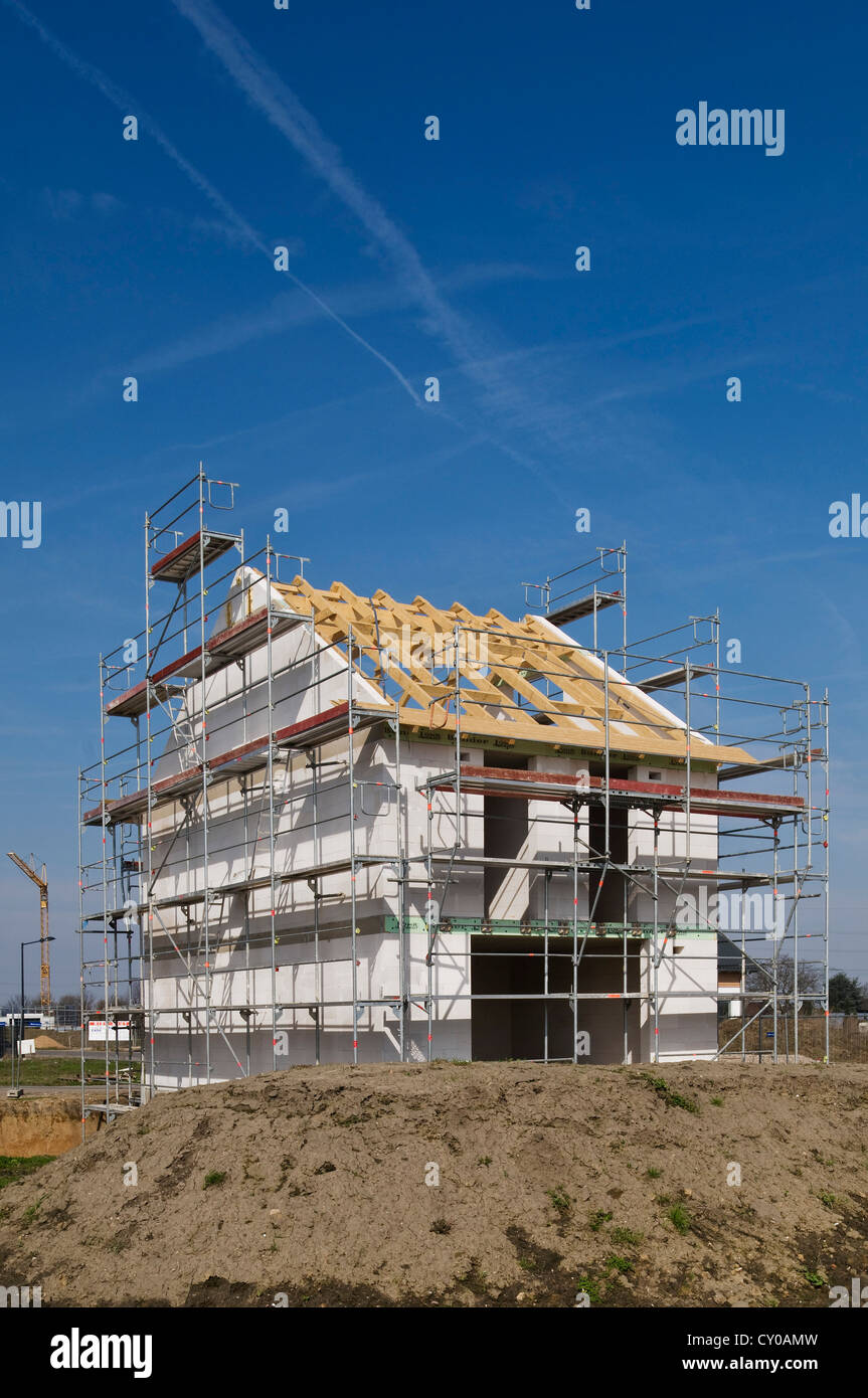 House construction site, building shell surrounded with scaffolding, with a crane in the distance, Erftkreis district Stock Photo