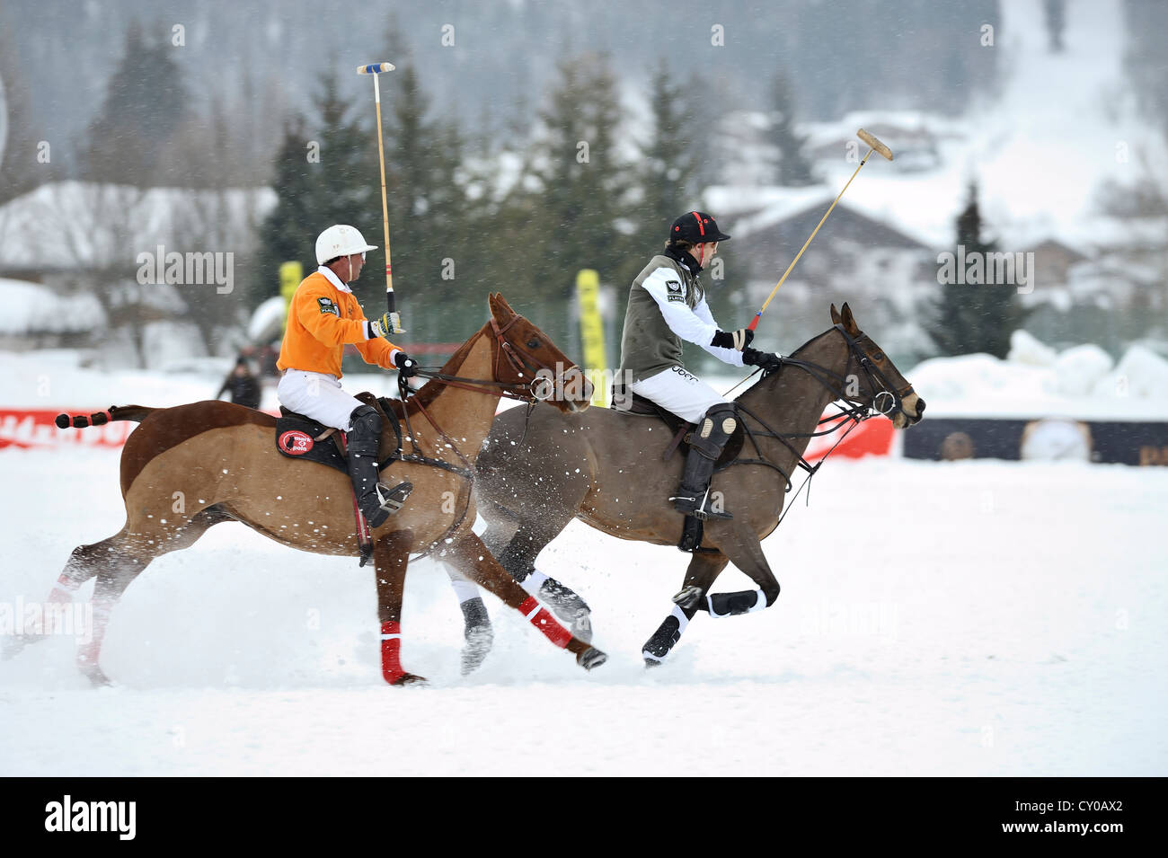 Two polo players galloping through the snow, Tarquin Southwell of team 'Hawker Beechkraft' followed by Francisco Podesta of team Stock Photo