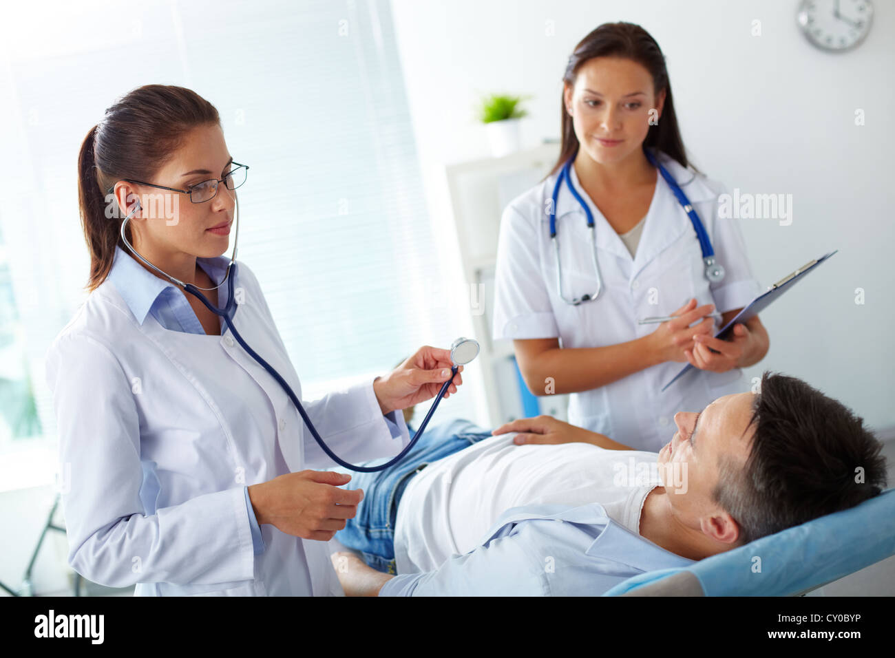 Portrait of two female doctors looking at patient during medical treatment in hospital Stock Photo