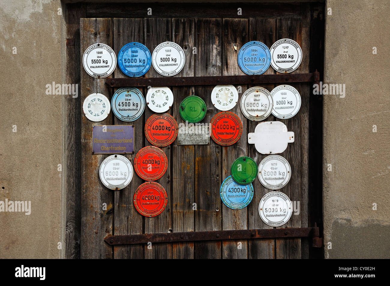 Award plaques on a barn door for the annual milk yield of cows, Wildenfels, Upper Franconia Stock Photo