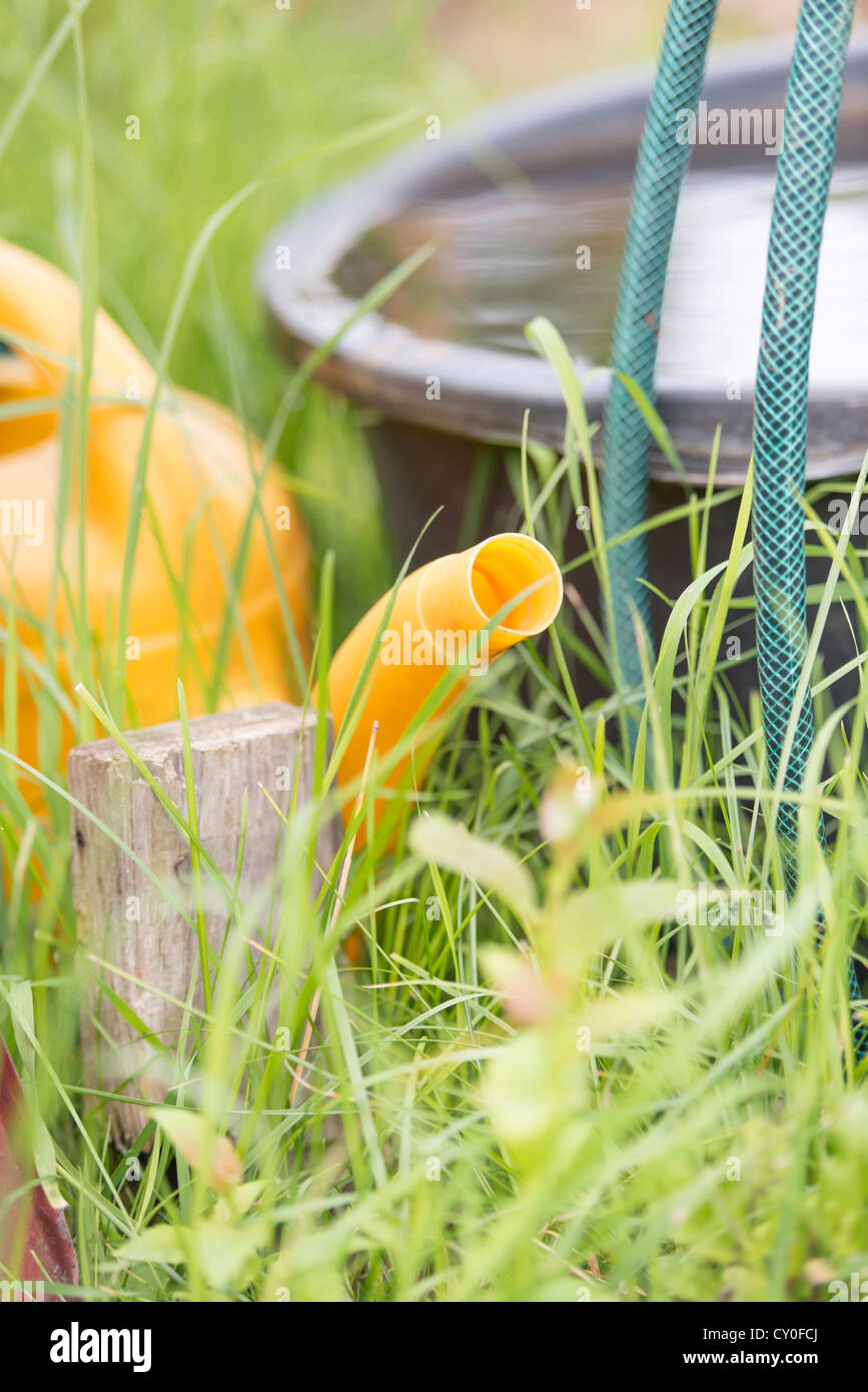 Closeup of plastic garden tools. Watering can, hose and bucket filled with water Stock Photo