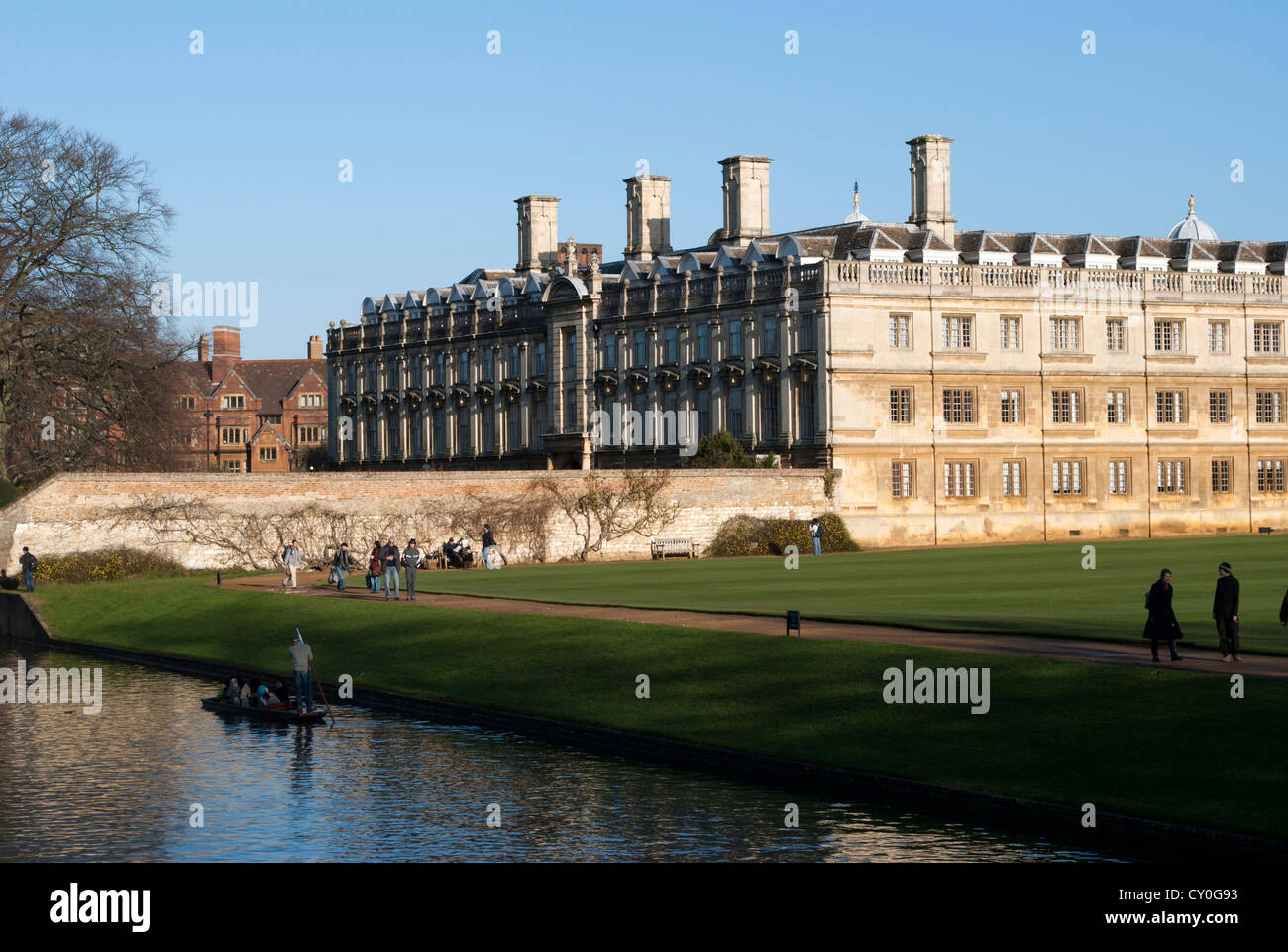 The Old Court of Clare college next to the Cam with a punt and tourists walking on the bank Stock Photo