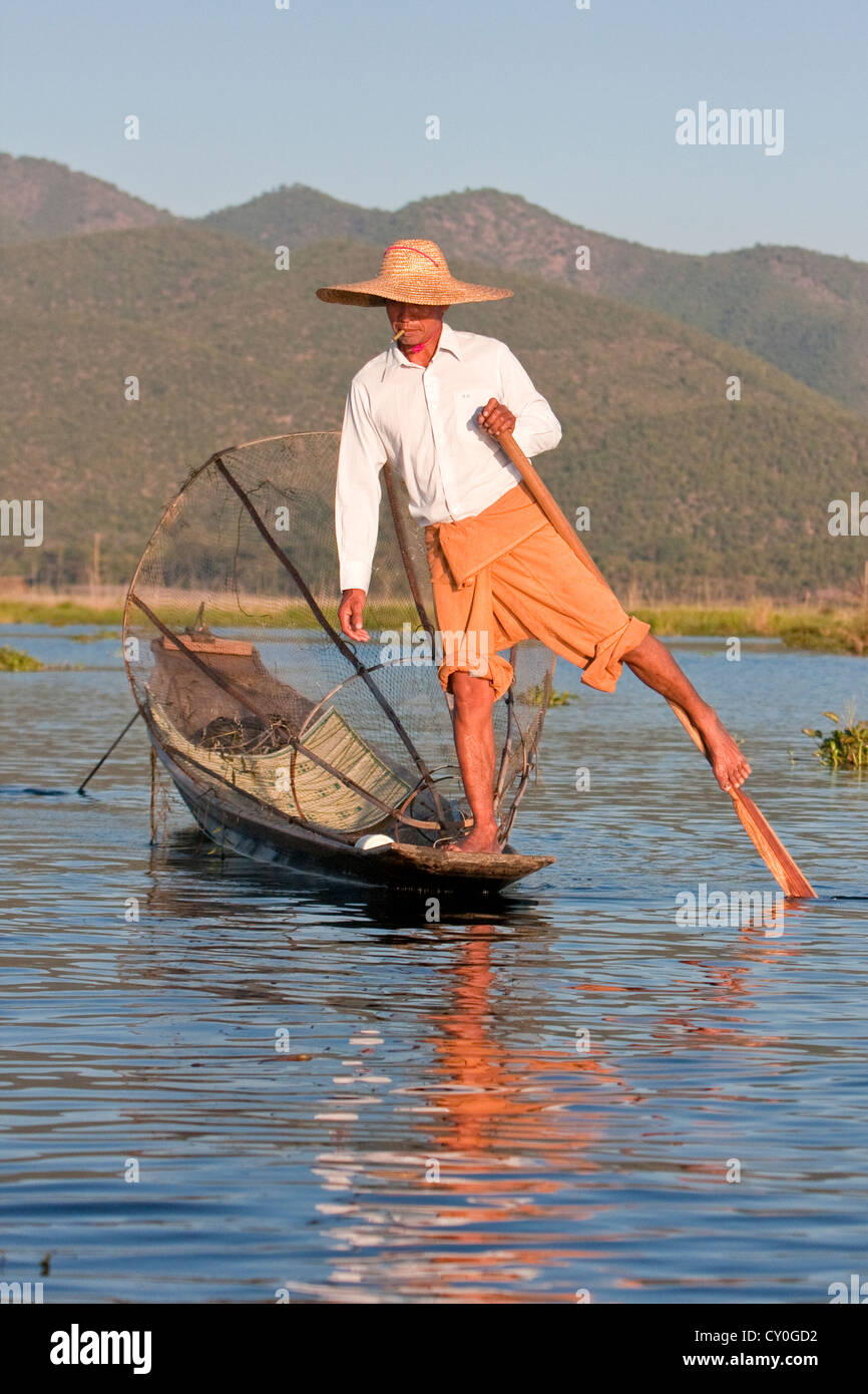 Myanmar, Burma. Fisherman rowing his canoe with one leg, in the style