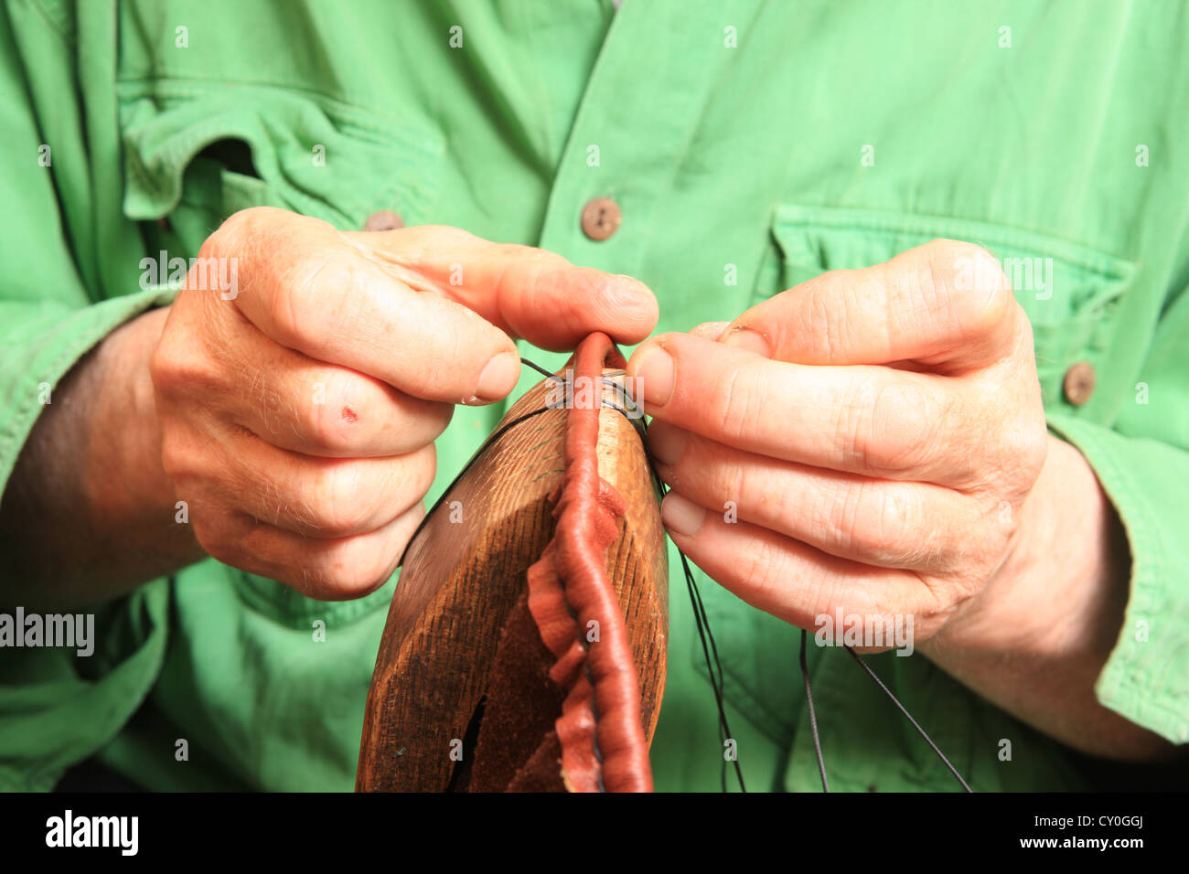 Julian Goodacre Bagpipe maker in Peeples Scotland.  Working on a set of pipes, sewing the leather air bag, using a clamp. Stock Photo