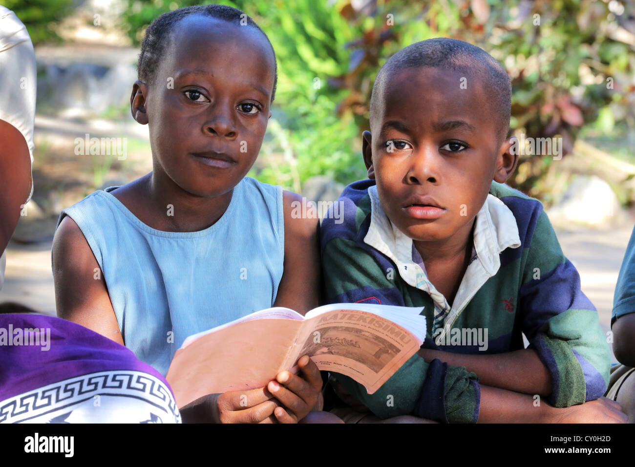 Pupils during the catholic religious education read in a catechesis book. Bagamoyo, Tansania Stock Photo