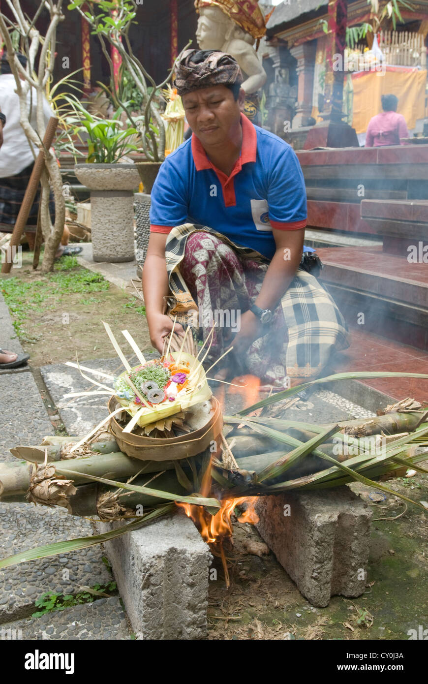 A man stokes a ritual fire of bamboo and offerings at an Animist ...