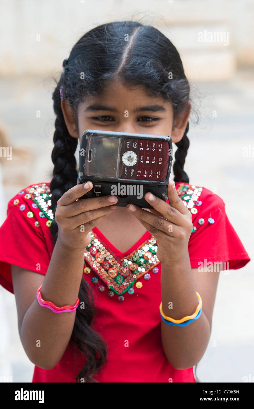 Indian girl playing a game on an old mobile phone in a rural indian village. Andhra Pradesh , India Stock Photo