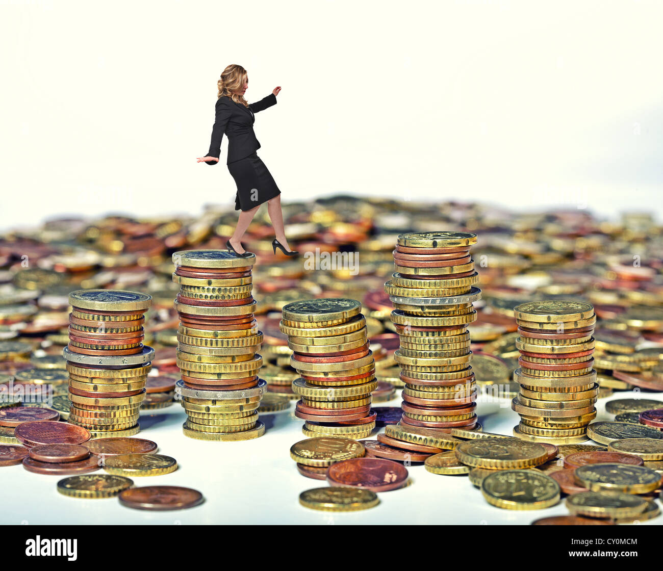 businesswoman walk on euro coin piles Stock Photo