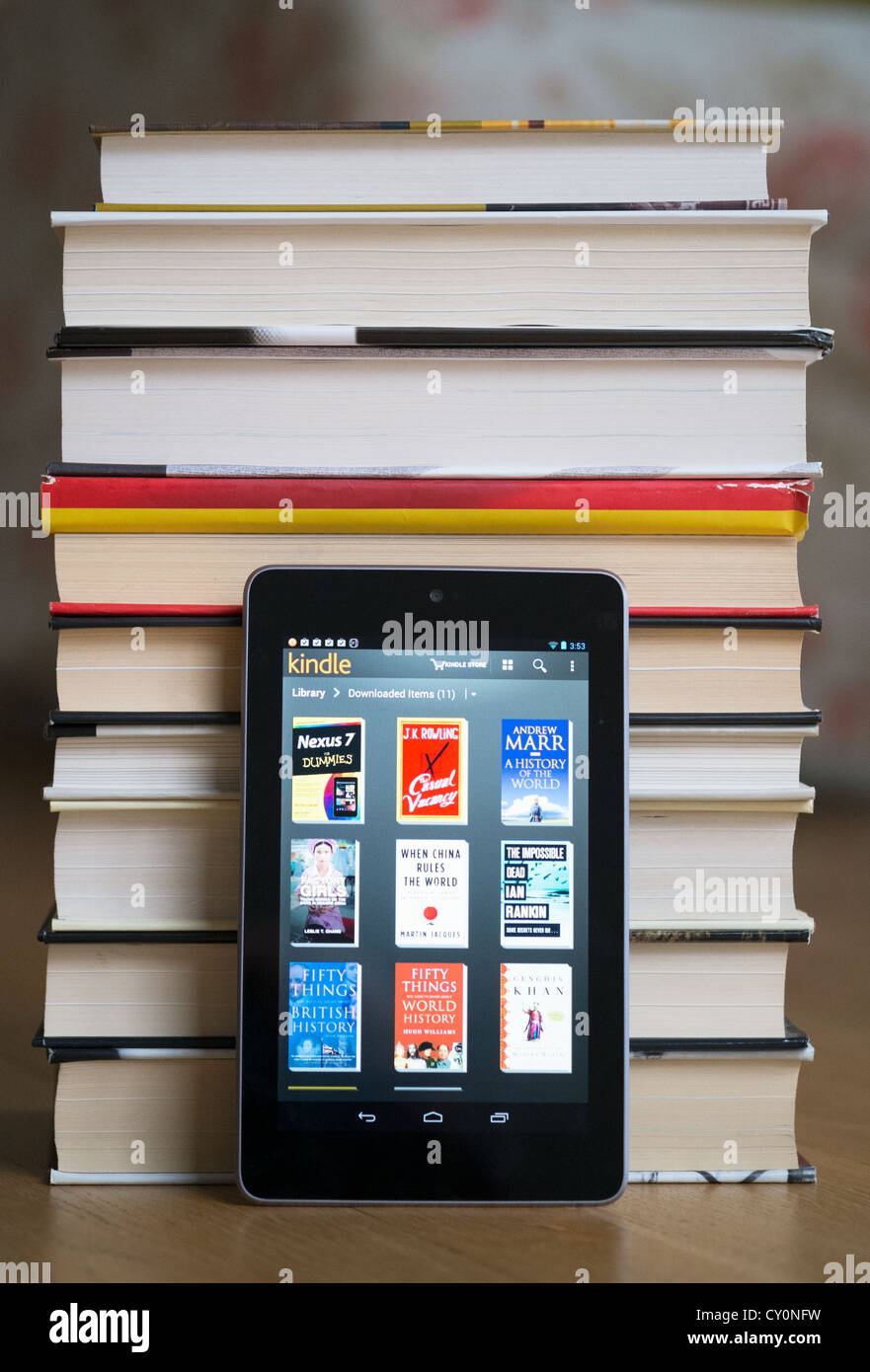 Google Nexus 7 tablet computer with kindle e-book library application and pile of traditional hardback paper books Stock Photo