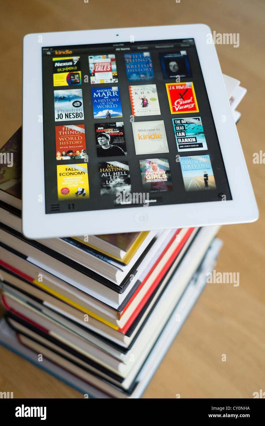 iPad tablet computer with kindle e-book library application and pile of traditional hardback paper books Stock Photo