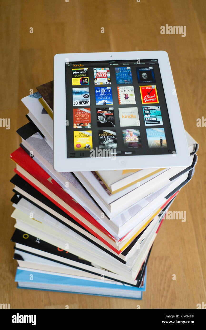 iPad tablet computer with kindle e-book library application and pile of traditional hardback paper books Stock Photo