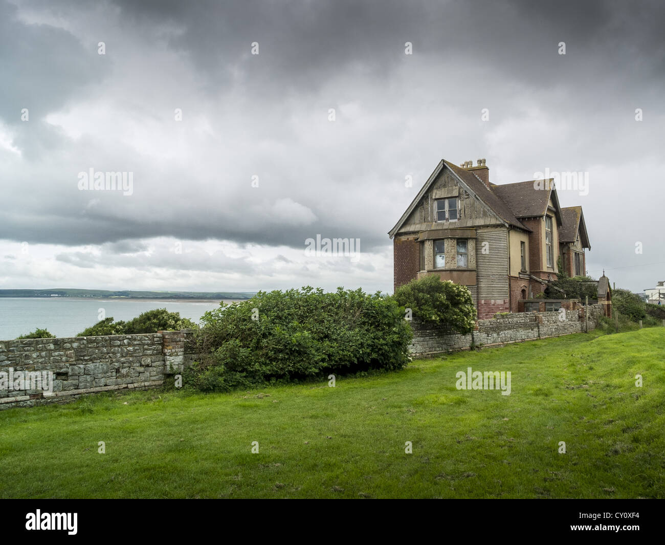 An abandoned derelict spooky looking house on a cliff edge under storm threatening skies. Westward Ho! North Devon. UK Stock Photo