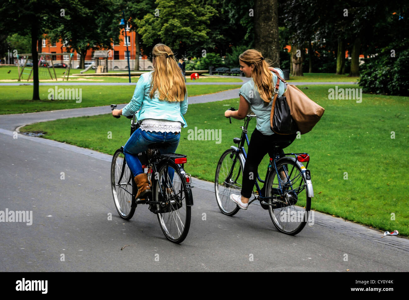 Two dutch girls riding their bicycles through the park in Breda