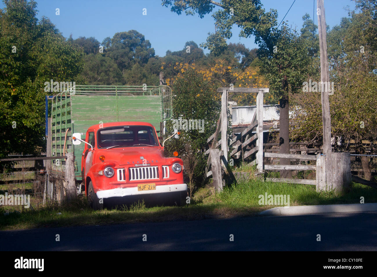 Old red Bedford truck parked off road next to wooden fence with trees behind Cessnock Hunter Valley New South Wales Australia Stock Photo