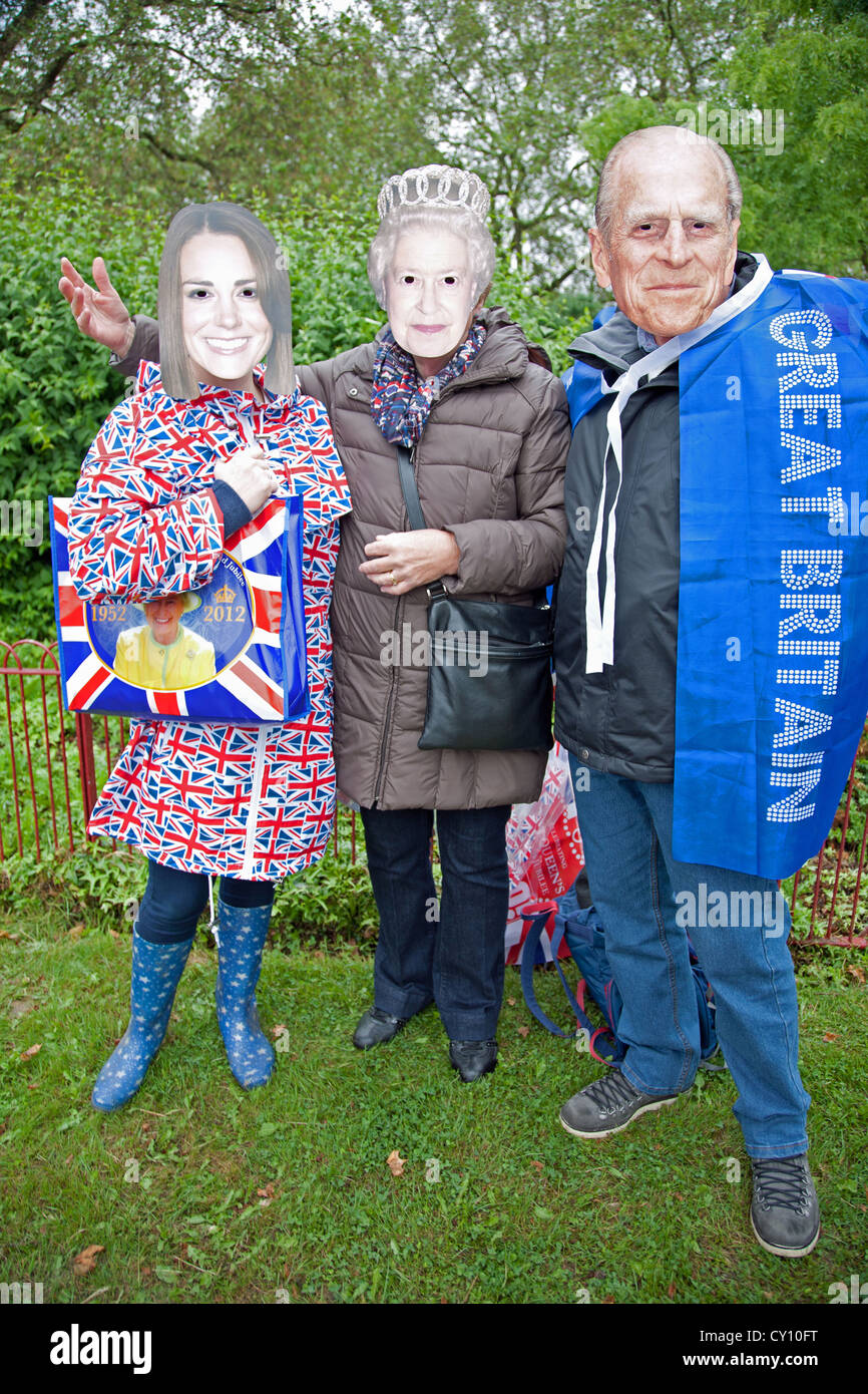 England. London. Three people with face masks of Queen Elizabeth II, the Duke of Edinburgh and Katherine, Duchess of Cambridge. Stock Photo